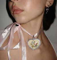 a woman wearing a necklace with a heart on it